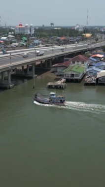 Bir gemi, üzerinde arabalar olan bir köprüye yakın yelken açar - FHD dikey drone videosu