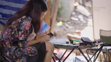 Esmer bir kadın telefonuna bakarken ayakkabısına resim yapıyor. 4K Yatay Video.