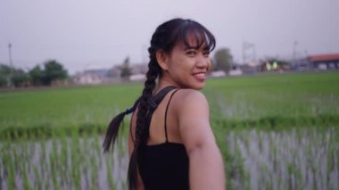 Taylandlı kız kameramanla el ele tutuşup kırsal alanda yürüyor.