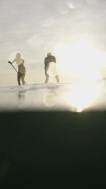 Gün batımında sörf tahtalarında bir çift silueti - FHD Dikey