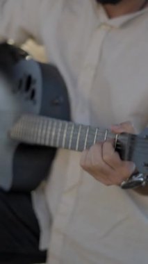 Kırsal kesimde gitar çalan İspanyol sakallı hippi. Geri çekil, yavaş çekim. Dikey FullHD video.