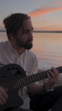 Günbatımında Torrevieja Pembe Gölü 'nde gitar çalan İspanyol sakallı adam Alicante - Dikey FullHD video
