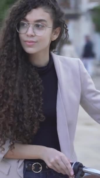 迷人的年轻女性模特在眼镜与长卷头发与自行车在户外散步 垂直方向 — 图库视频影像
