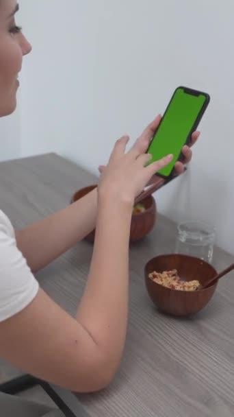 坐在厨房厨房里的一个女人用手指触摸她智能手机的绿色屏幕的侧视图 Closeup Shot垂直射击 — 图库视频影像