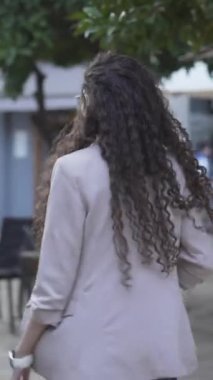 Paltolu Faslı kız ve uzun kıvırcık saçlı adam bisiklet süren bir adamla sokakta yürüyor. - İzleme çekimi - Dikey