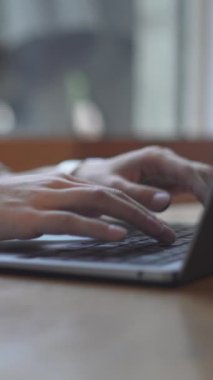 Bir kadın laptopta bir fincan sıcak kahveyle çalışıyor ve daktilo kullanıyor. - Kapat - Dikey