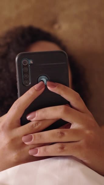 スマートフォンは ベッドで認識できない女性によってテキストされています Fhd垂直ビデオ — ストック動画
