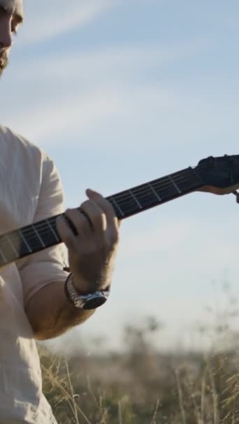 秋天日落时分 大胡子西班牙男子吉他手在天空下弹奏吉他手的肖像 垂直Fullhd视频 — 图库视频影像
