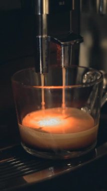Espresso makinesinden akan kahve bardağa damlıyor. Ofiste kahve hazırlıyorum. Kapat - Dikey