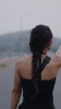 Asyalı bir kız yolda yürüyor ve kollarını hareket ettiriyor - 4K yatay yaşam tarzı videosu