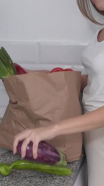 Mutfak tezgahına taze çiğ sebze koyan kadın. El bilgisayarı - Dikey