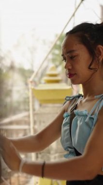 Asyalı bir kadın tapınağın ortasında gong çalıyor - FHD dikey video