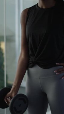 Tanımlanamayan Afrikalı Amerikalı kadın spor salonunda dambılla egzersiz yapıyor - yaşam tarzı - FHD dikey video