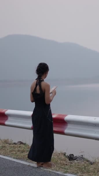 Menina Olha Para Seu Telefone Celular Frente Lago Montanha Deslumbrante — Vídeo de Stock