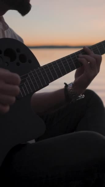 Silhouetted Manos Hombre Tocando Guitarra Playa Junto Lago Atardecer Dorado — Vídeos de Stock