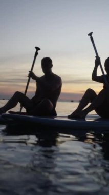 Koh Tao 'da bir plajda kürek çeken çift FHD dikey sörf tahtası.