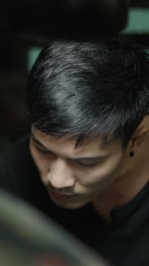 Genç Asyalı bir adam stüdyosundaki müşterisine dövme yapıyor yaratıcı konsept FHD dikey video