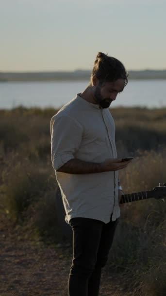 Man Guitarist Holding Guitar Making Call Using Mobile Phone While — Stock Video