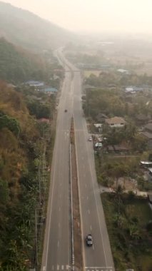 Ormanlık bir bölgenin ortasındaki bir yolun gökyüzünden görünümü - Endüstri HD Dikey