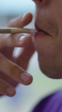 Tanınmayan bir adamın ağzı, FullHD dikey bir videoda tüttürüyor.