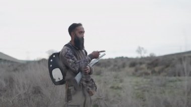 Silahlı bir avcı çalılıktaki bir şeyi işaret ediyor - 4K Yatay Görüntü
