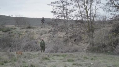 Bir avcı, arkadaşı ve bir köpekle bir yuvanın yanında yürüyor - 4K Yatay video