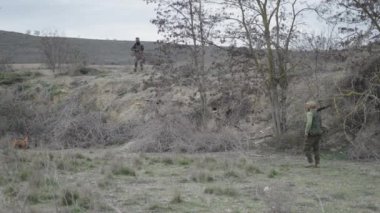 İki avcı ve bir köpek gelinciğin çalışmasını gözlemliyor - 4K Yatay video