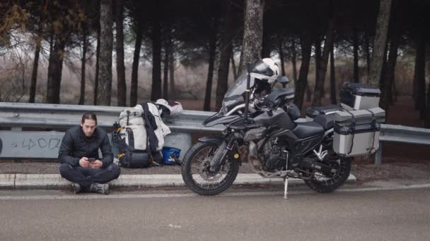 彼のバイクの隣に携帯電話を持っている大人の男 4K水平ビデオ — ストック動画