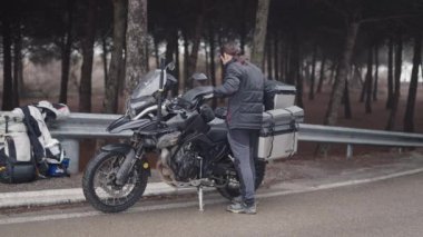 Kafkasyalı bir adam motosikletindeki kickstand 'ı kaldırıyor - 4K yatay video