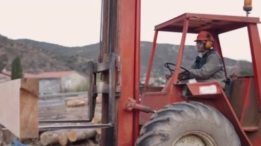 Bir işçi bir odun parçası alıyor ve kesiciye yerleştiriyor - 4K Yatay video