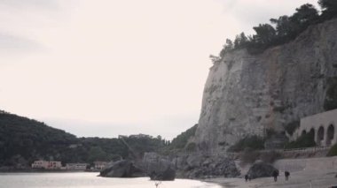 Dağlık güzel bir plajın kumsalındaki insanlar - 4K yatay video