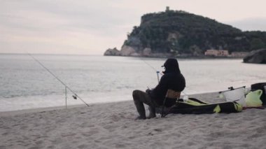 Tanımlanamayan balıkçı balık tutarken cep telefonuna bakar - 4K Yatay video