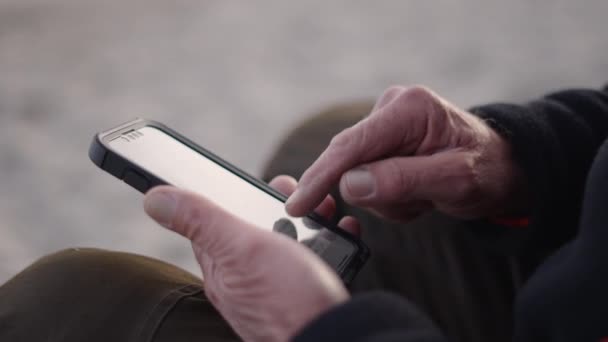 Handen Van Een Oudere Visser Die Een Mobiele Telefoon Aanraakt — Stockvideo