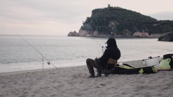 認識できない漁師が釣りをしている間に携帯電話を見る 4K水平ビデオ — ストック動画