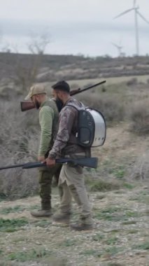 Silahlı iki avcı yürür ve selam verir - FullHD dikey video