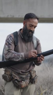 Bir avcı tüfeğini doldurur ve kameraya gülümser - FullHD dikey video