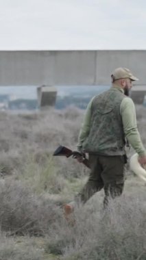 Avlanmak için bir gelincik taşıyan şapkalı bir avcı - FullHD dikey video
