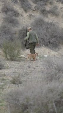 Gelincik taşıyan bir avcının yanında bir köpek FullHD dikey video