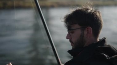 Gözlüklü bir balıkçı oltasındaki yemi manipüle eder - 4K Yatay