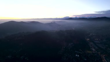 Dağlardaki sisli bir köyün havadan görünüşü - 4K Yatay