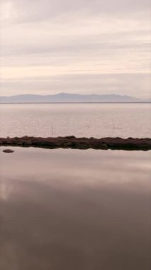 İnsansız hava aracı gün batımında güzel göl üzerinde uçar - FHD dikey video
