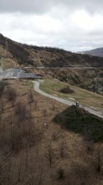 Dağların arasında bir motosiklet yol boyunca ilerliyor - FHD dikey video