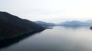Dağlarla çevrili Maggiore Gölü 'nün gökyüzünden görünüşü - Yatay 4K Maggiore Gölü