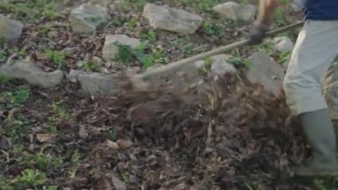 İş kıyafetleri içinde tanınmayan bir adam yaprakları süpürüyor - yatay 4K