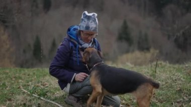 Kafkasyalı yetişkin kadın şapkalı mutlu agacahda Alman çoban köpeğini okşuyor - 4K Yatay video