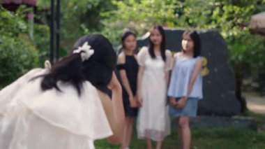 Üç Asyalı genç kız kameraya poz verirken arkadaşları yazın büyük taşın yanında onların fotoğrafını çekiyor. 4K Yatay Video.