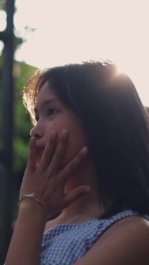 Ağır çekimde genç Asyalı kız yazın arka planda kameraya bakıyor FullHD dikey video