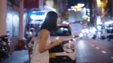 Güzel bir kadın elinde cep telefonuyla karşıdan karşıya geçiyor. 4K yatay video.