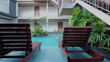 Asyalı genç bir kadın Bangkok Tayland ve otel havuzunda banyo yaparken elleriyle yüzünü ovuyor. 4K yatay video.