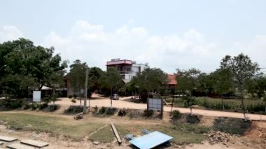 Vietnam 'da göl oteline erişen ağaçlar arasındaki kırsal yolun panoramik drone görüntüsü - 4K Yatay Video